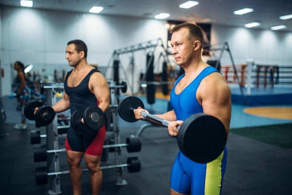 Hombres levantando pesas en gimnasio.