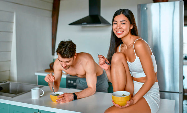 Pareja desayunando saludable en cocina.
