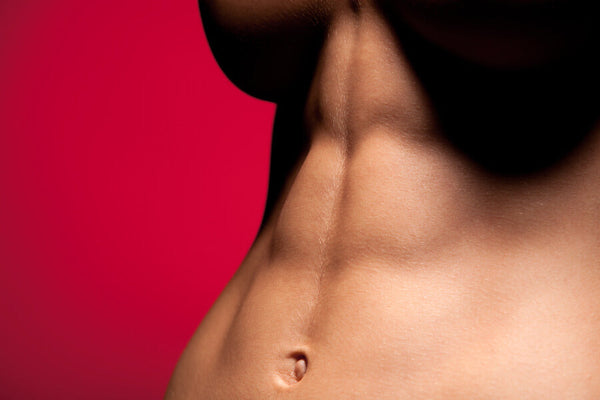 Torso femenino con abdomen definido sobre fondo rojo.