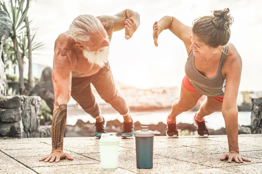 Pareja entrenando en flexiones con botellas deportivas