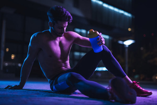 Hombre descansando después de entrenar con shaker en mano.