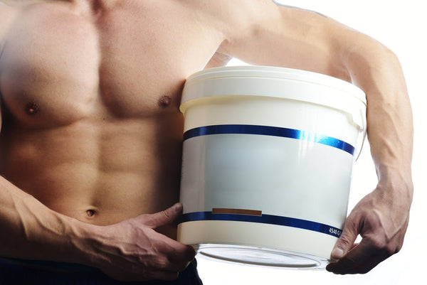 Hombre musculoso sosteniendo envase de suplemento proteico en polvo