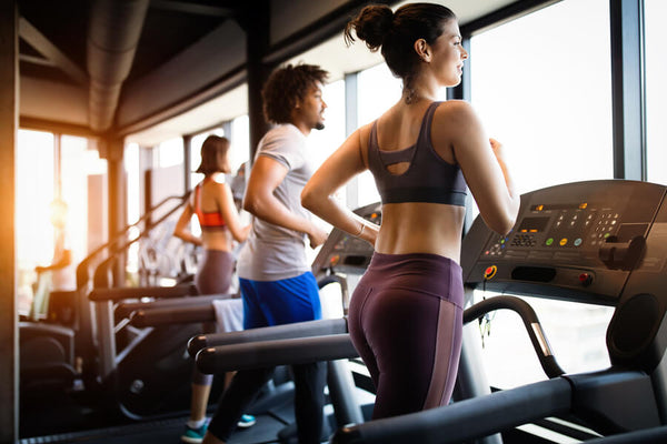 Personas corriendo en cintas en gimnasio.