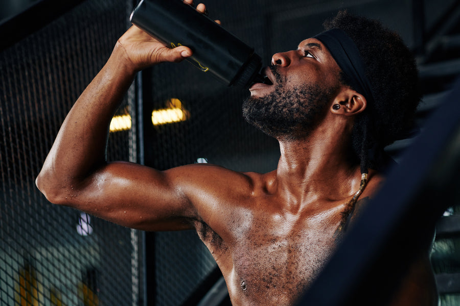 Hombre haciendo ejercicio bebiendo agua de botella en gimnasio