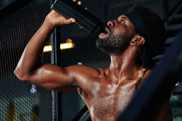 Hombre haciendo ejercicio bebiendo agua de botella en gimnasio