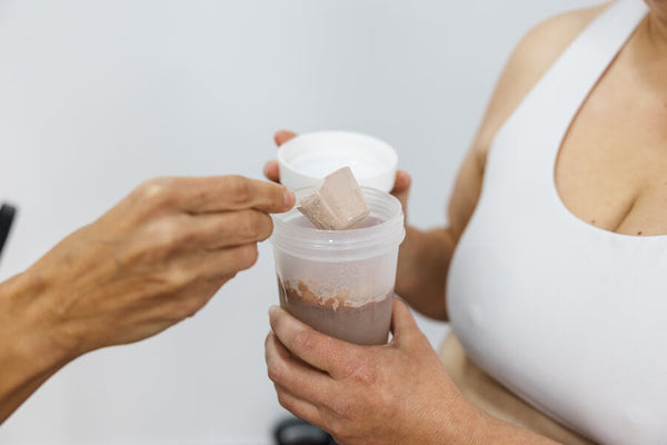 Persona añadiendo proteína en polvo a un shaker.
