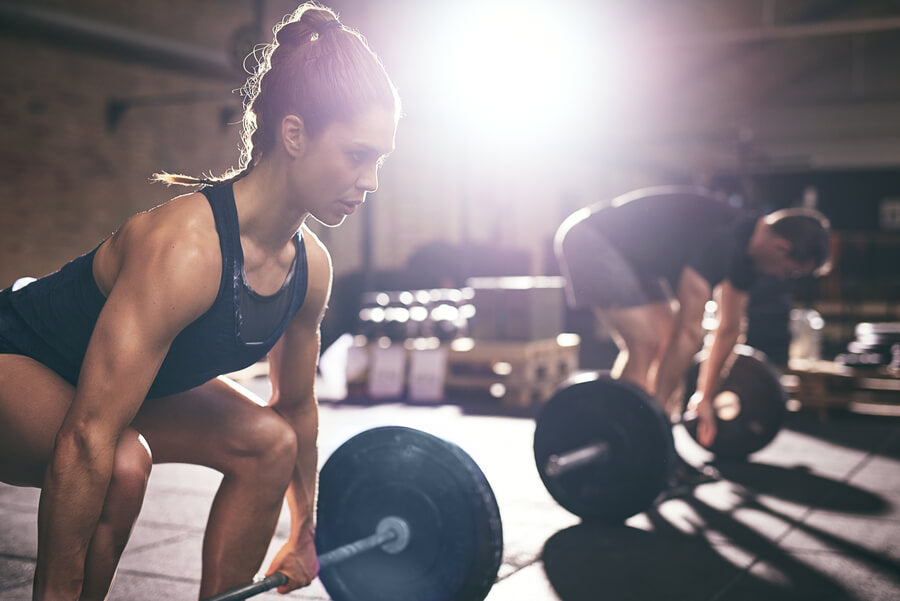 Proteína de carne suplemento - Atletas levantando pesas en gimnasio con luz intensa.