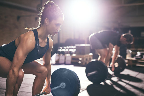 Proteína de carne suplemento - Atletas levantando pesas en gimnasio con luz intensa.