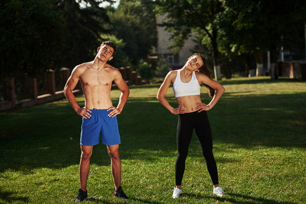 Hombre y mujer estirando en parque al aire libre.