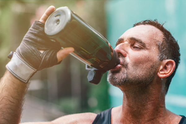 Hombre bebiendo batido proteico después de entrenar.