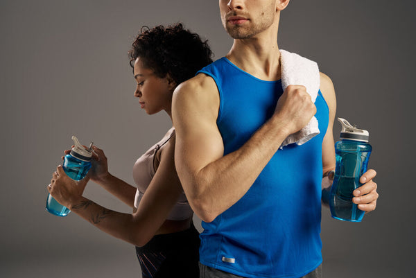 suplementos deportivos para quemar grasa - Hombre y mujer deportistas de espaldas sosteniendo botellas de agua azul.
